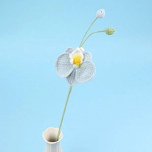 Détail d'orchidée papillon crochetée à la main bleue avec boutons en vase céramique