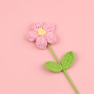 Fiore a sbuffo all'uncinetto rosa e giallo con foglie verdi su sfondo rosa