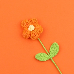 Dettaglio di fiore a sbuffo fatto a mano all'uncinetto con petali arancioni e stelo verde