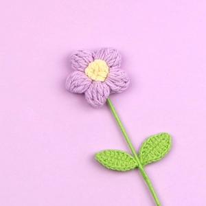 Dettaglio di un fiore a sbuffo lavorato a maglia con petali di lana testurizzati viola