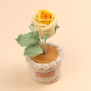 Detail of hand-crocheted yellow rose with green leaves and a leather handmade label