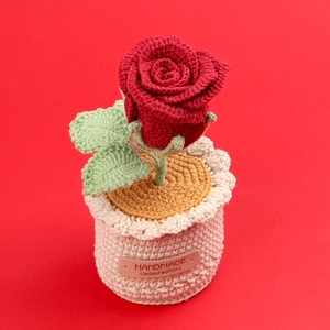Detail of handmade crocheted red rose in pot with leather handmade label and knit texture