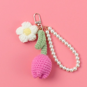 Detail von rosa gestricktem Tulpen-Schlüsselanhänger mit kleiner Blume und Perlenkette