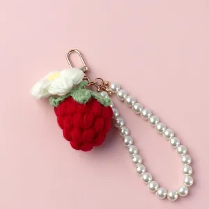 Detail of handmade crochet strawberry keychain with white flower and pearl bead strap