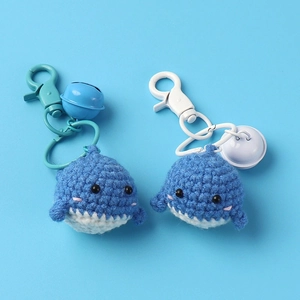 Detail of handmade crochet whale keychains with cute bells and blue-white knit textures