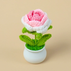 Close-up of handmade pink knitted rose in a white pot with detailed crochet textures