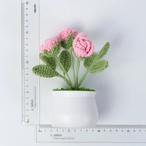 Close-up of handmade pink crochet roses in a white pot with measurement scales