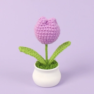 Close-up of handmade crochet tulip in white ceramic pot with detailed stitch texture