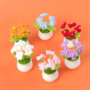 Detailed view of six colorful handmade crochet flower pots with pearl accents on orange background