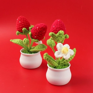 Detailed view of two handmade crochet strawberry potted plants with red berries and green leaves