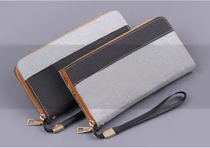 Detail of two-tone canvas wristlet wallets featuring dual-color stitching and metal zippers