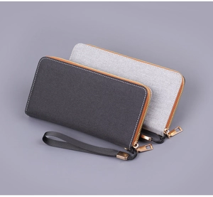 Detail of canvas long wallets featuring gold zippers and fabric texture in grey shades