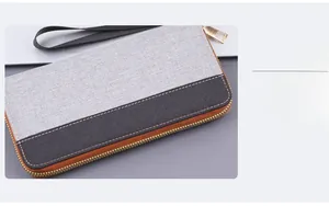 Detail of grey and black canvas men's wallet showing stitching and gold metal zipper