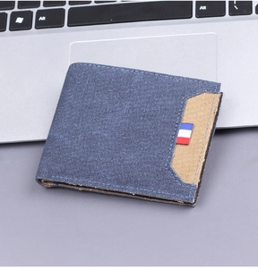 Detail of slim blue canvas wallet with tricolor ribbon on silver laptop keyboard