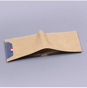 Close-up of khaki canvas bifold wallet with denim blue panel and striped ribbon detail
