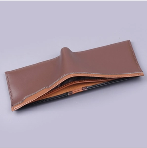 Detail view of bi-fold men's wallet with brown leather stitching and striped fabric lining