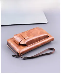 Detailed view of a brown faux leather long clutch with a wrist strap and metal zipper