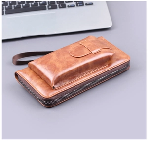 Macro detail of brown leather clutch bag with multi-layer zipper and secure wrist strap