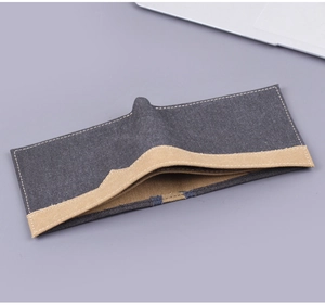 Détail du portefeuille en toile gris foncé avec bordures contrastées en tissu beige