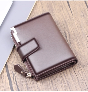 Detail of dark brown short leather wallet with snap closure and zipper on wooden desk