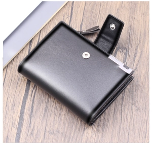 Detailed view of a black leather vertical wallet with snap closure on a wooden background
