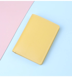 Primer plano de un tarjetero de cuero amarillo con costuras blancas y textura fina