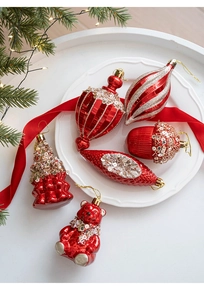 Detailed view of red Christmas ornaments including a bear and pine cone on a white tray