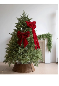 Detailed view of large burgundy velvet Christmas bows hanging on a warm lit festive tree