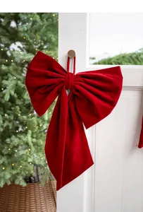 Macro shot of large burgundy velvet bow hanging on a white door for Christmas decor