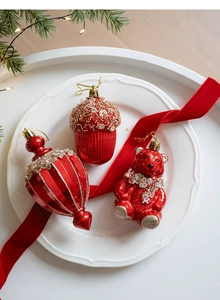 Close-up of pearl red Christmas ornaments featuring bear, acorn, and lantern shapes