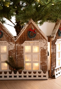 Détail de clôture de Noël en bois illuminée avec maisons et petits nœuds rouges