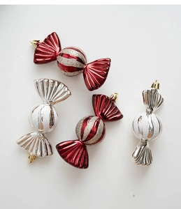 Close-up of red and silver Christmas candy ornaments with glitter stripes and gold hooks