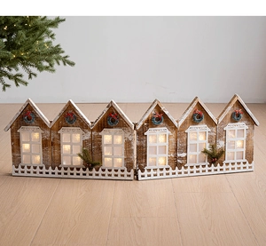 Détail d'un village de Noël lumineux en bois avec éclairage LED et décorations de clôture