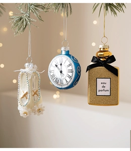 Dettaglio di scarpette, orologio e boccetta di profumo appesi all'albero di Natale