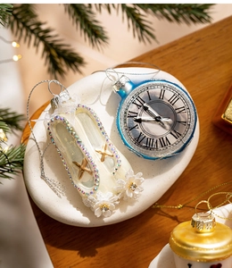 Dettaglio di ornamenti natalizi in vetro con orologio blu e scarpetta da ballo bianca