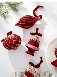 Macro detail of red flocked Christmas ornaments with gold glitter and velvet ribbons