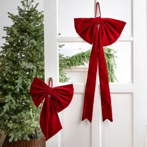 Large burgundy velvet Christmas bow set hanging on a white door for festive holiday decor