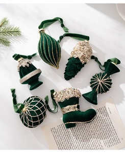 Detailed view of dark green velvet Christmas ornaments with gold glitter accents and hanging loops