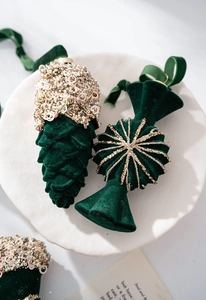 Macro detail of dark green velvet pinecone and candy ornaments with gold sequins