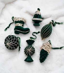 Detail of six dark green flocked Christmas ornaments with gold sequins on white faux fur