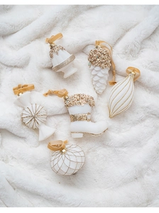 Detail of cream white Christmas ornaments with gold glitter on white faux fur background