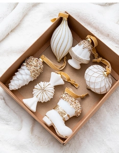 Macro detail of white flocked Christmas ornaments with gold glitter accents in a kraft box