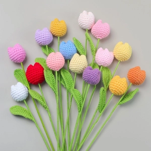 Flat lay of colorful handmade crochet tulips with detailed knit texture and green stems
