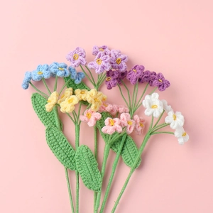 Detailed close-up of handmade crochet forget-me-not flowers in pastel color palette