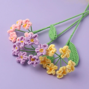 Detailed close-up of handmade crochet forget-me-not flowers in pastel pink, purple and yellow