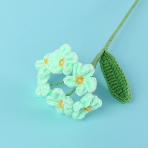 Detail of handmade crochet forget-me-not flower with mint green petals and yellow stamens
