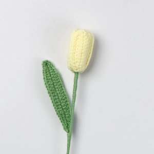 Detailaufnahme einer handgehäkelten Tulpe mit gelber Knospe und grünem Strickblatt
