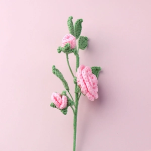 Dettaglio di camelia all'uncinetto rosa fatta a mano con trama a maglia fine