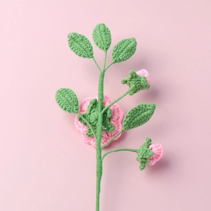 Dettaglio di camelia rosa fatta a mano all'uncinetto con petali delicati e foglie verdi