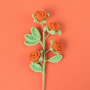 Handmade crochet orange rose with four flowers and green leaves on orange background